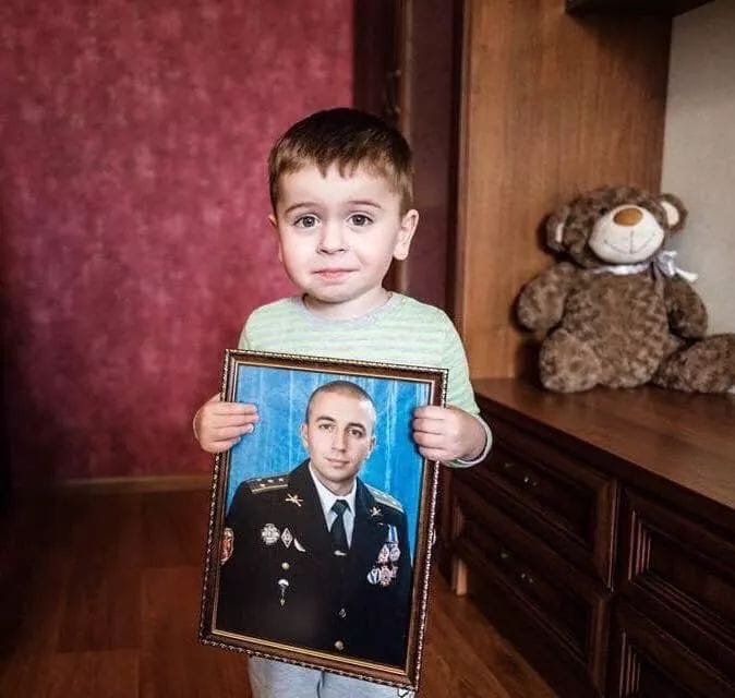 Вечная память погибшим за Украину - мальчик с портретом погибшего отца-героя.jpg